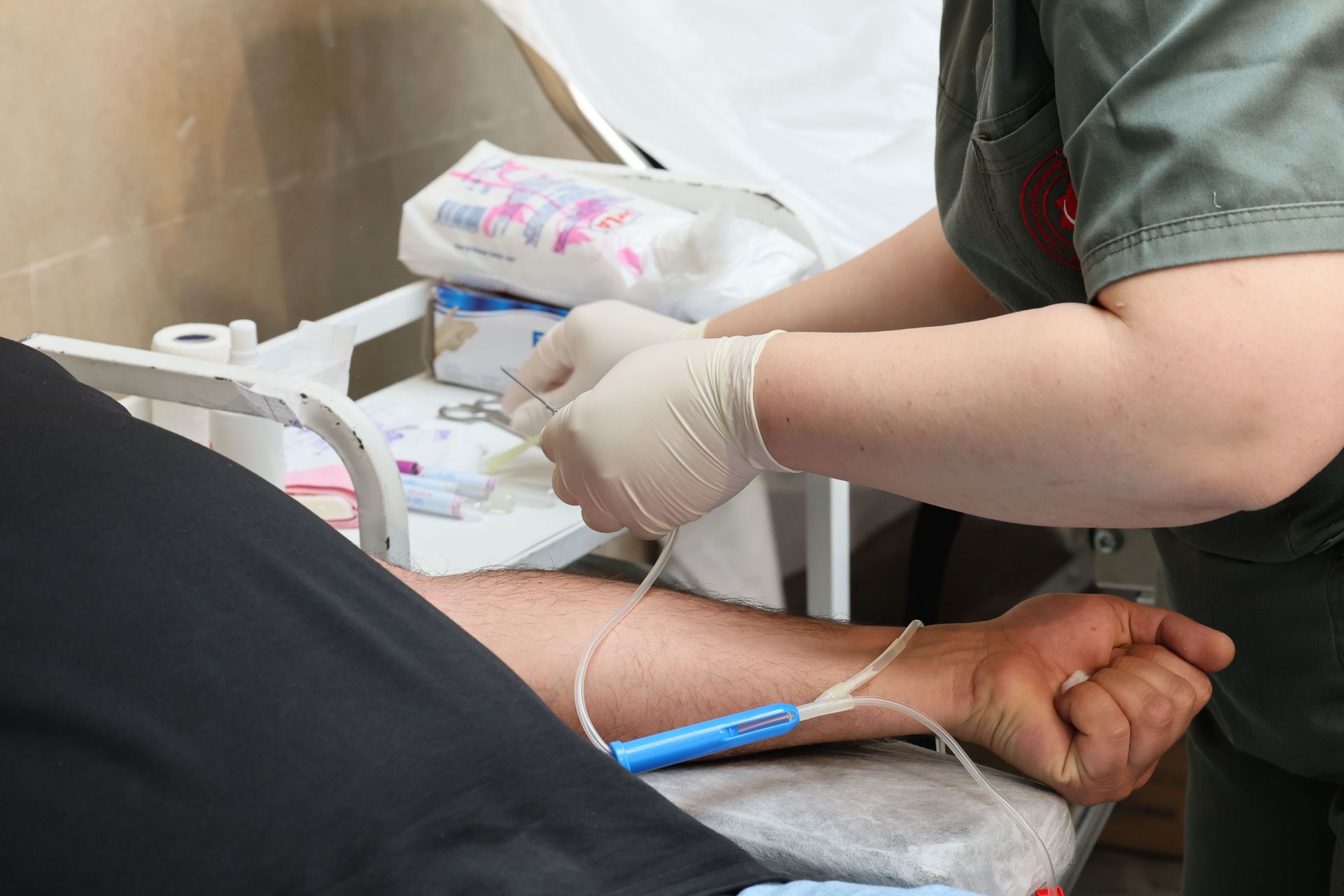 A healthcare worker drawing blood from a patient's arm in a clinical environment.