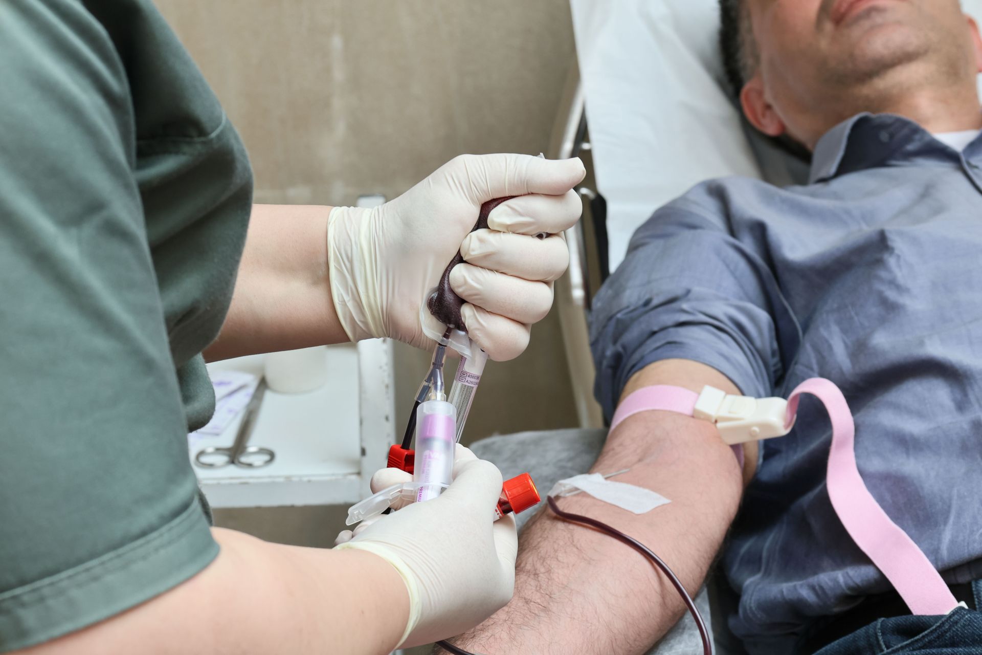 A healthcare professional drawing blood from a donor’s arm using a syringe.